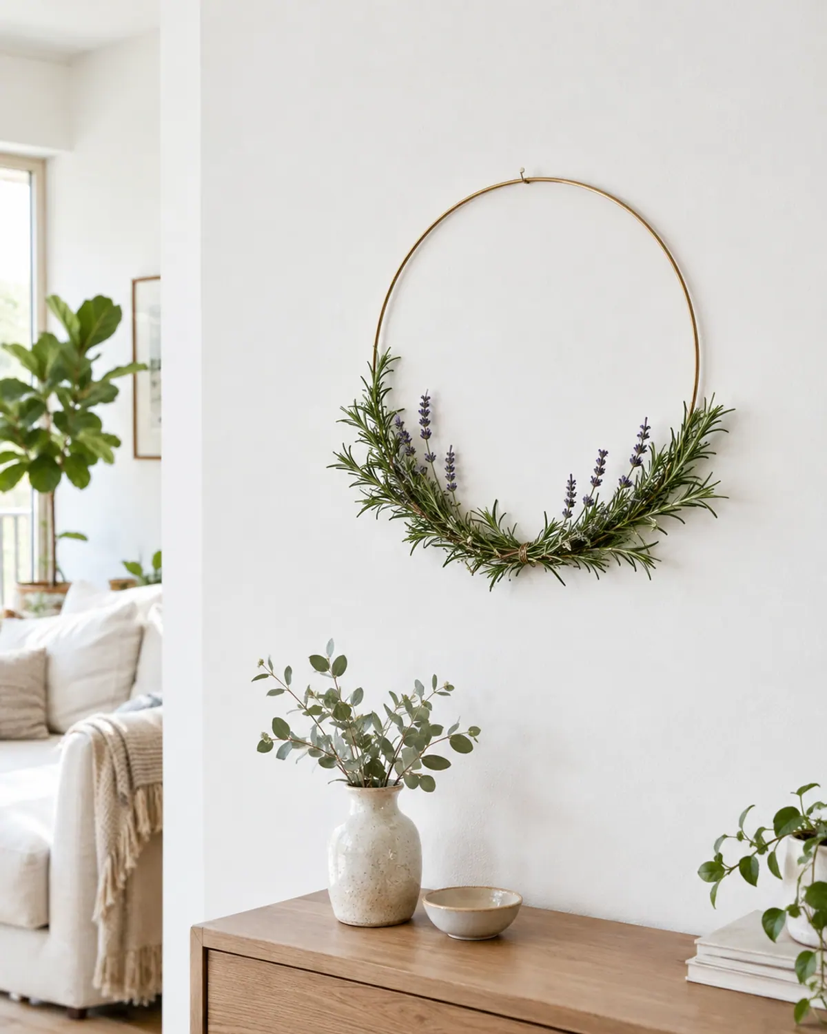 Modern herb wreath on a thin brass hoop with rosemary and lavender covering only the lower third, hanging on a white wall